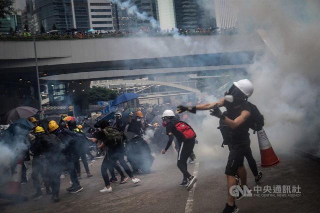 警方周六晚在政府总部外发射催泪弹，有示威者并未马上撤退，而是捡起催泪弹往回丢。（图片来源：中央社）