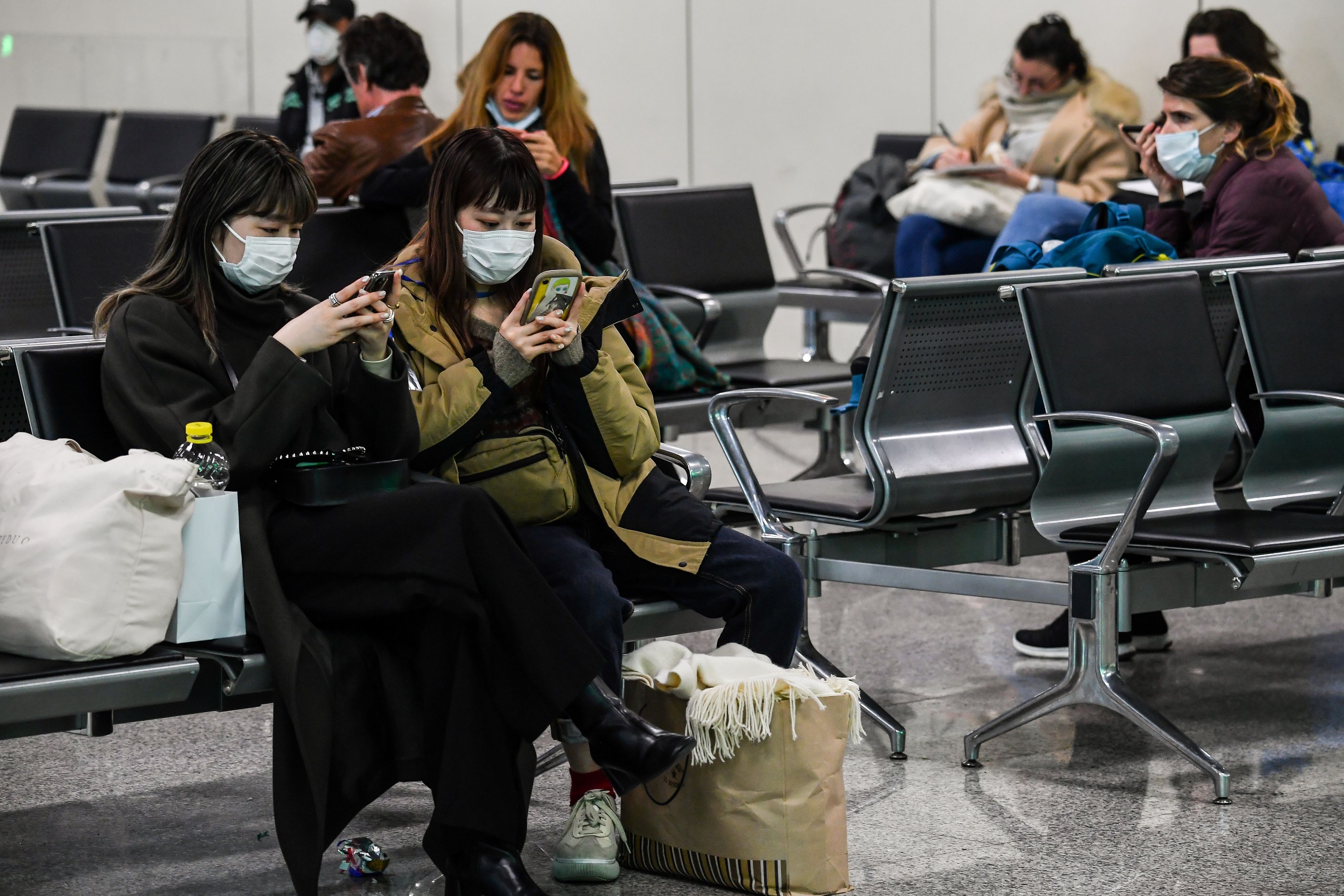 2020年3月13日，戴着口罩的乘客在意大利罗马菲乌米奇诺国际机场航站楼等候