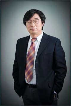 A person wearing a suit and tie smiling at the camera
Description automatically generated